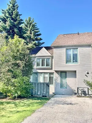 a white house with a gate and a tree at The Family Escape Townhome in Collingwood