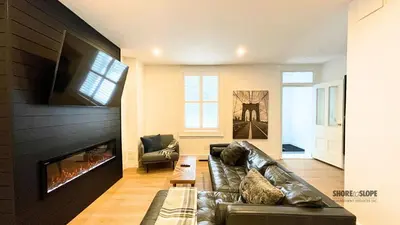 a living room with a leather couch and a fireplace at The 1883 Century Flat Suite in Collingwood