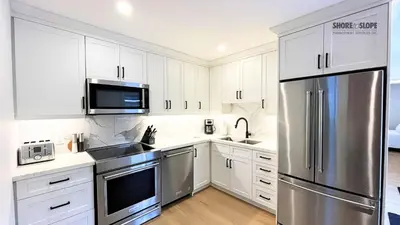 a kitchen with white cabinets and a stainless steel refrigerator at The 1883 Century Flat Suite in Collingwood