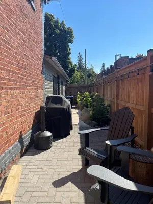 a patio with two benches and a brick building at The 1883 Century Flat Suite in Collingwood