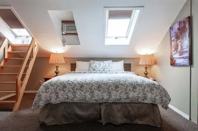 a bedroom with a bed and two lamps and a staircase at Stone Maiden Inn in Stratford