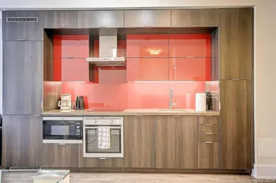 a kitchen with red walls and wooden cabinets at Skyline Suites - Walk to MTCC, ACC, Rogers Centre & Entertainment District in Toronto