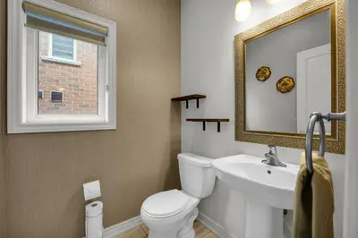a bathroom with a toilet and a sink and a mirror at Spacious Family Friendly Vacation home in Brampton