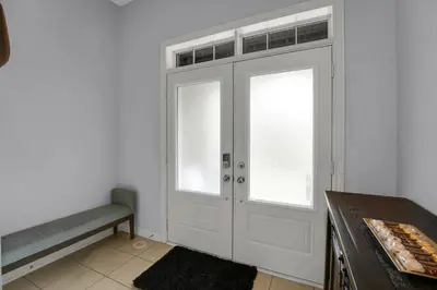 a white door with two windows and a bench at Spacious Family Friendly Vacation home in Brampton