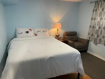 a bedroom with a white bed and a chair at Travelers Home in Oshawa