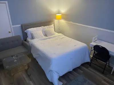 a bedroom with a white bed and a chair at Travelers Home in Oshawa