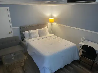 a bedroom with a bed and a chair and a lamp at Travelers Home in Oshawa