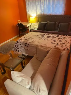 a bedroom with a bed with a couch and a table at Comfort Quest in Oshawa