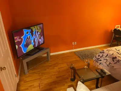 a living room with a flat screen tv on a table at Comfort Quest in Oshawa