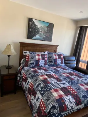 a bedroom with a bed with a quilt on it at Motel 400 & Suites in Innisfil