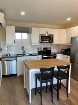 a kitchen with white cabinets and a wooden table with chairs at Motel 400 & Suites in Innisfil