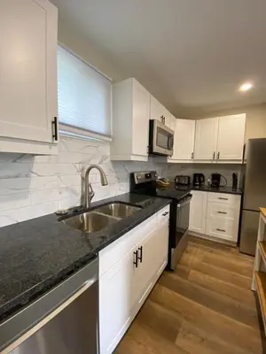 a kitchen with white cabinets and a sink at Motel 400 & Suites in Innisfil