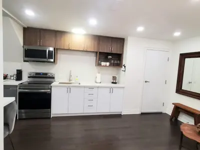 a kitchen with white cabinets and a black stove at Dufferin Serenity Suite in Toronto