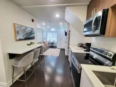 a kitchen and living room with a counter and chairs at Dufferin Serenity Suite in Toronto