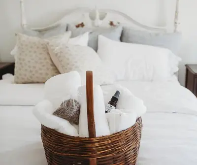 a basket with towels and a bottle of wine on a bed at Vintage Farmhouse with Hot Tub on Vineyard in Waterford