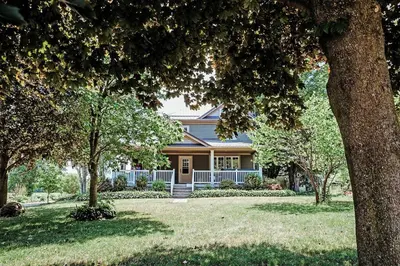a house with trees in front of a yard at Vintage Farmhouse with Hot Tub on Vineyard in Waterford