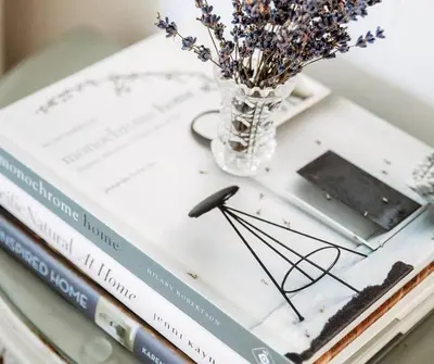 a stack of books on a table with a vase of flowers at Vintage Farmhouse with Hot Tub on Vineyard in Waterford