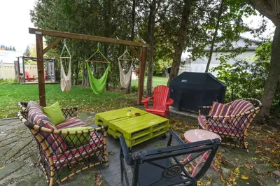 a patio with a table and chairs and a swing at Danby House in Markdale