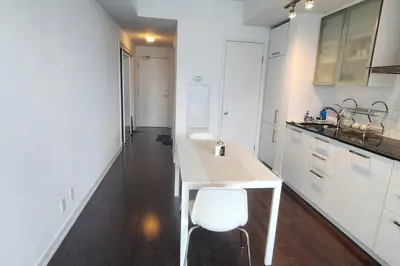 a white kitchen with a table and a white chair at Modern studio High Floor ,CN Tower, ScotiaArena in Toronto