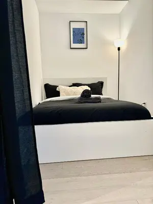 a white bedroom with a bed with a black blanket at Elegant Condo Near Eaton Centre Mall in Toronto