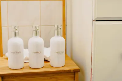 three bottles sitting on a wooden table next to a refrigerator at Lum The Queen in Toronto