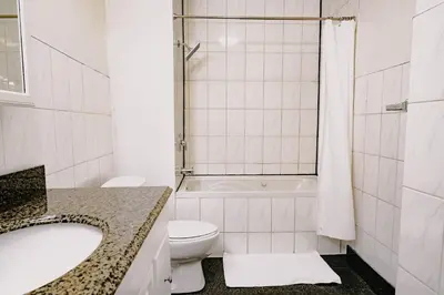 a white bathroom with a toilet and a sink at Lum The Queen in Toronto