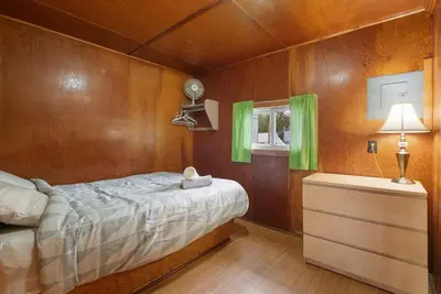 a bedroom with a bed and a dresser with green curtains at Peaceful Getaway in Bailieboro