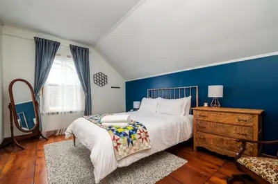 a bedroom with a large bed and a blue wall at The Marigold - Gorgeously remodelled PEC farmhouse in West Lake