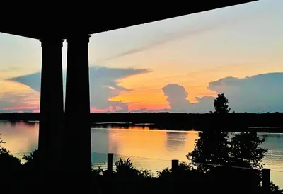 a sunset over a body of water with a house at Lakeside Maison in Hillier