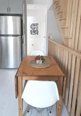a wooden table with two white chairs and a refrigerator at KozyStay Toronto in Toronto