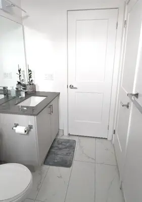 a white bathroom with a toilet and a sink at KozyStay Toronto in Toronto