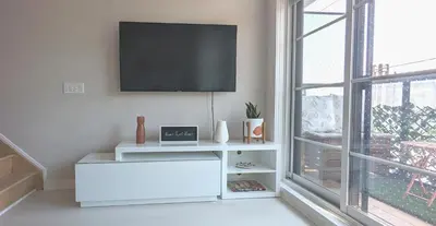 a white living room with a flat screen tv on a wall at KozyStay Toronto in Toronto