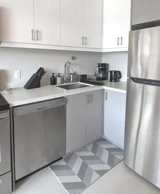 a kitchen with white cabinets and a stainless steel refrigerator at KozyStay Toronto in Toronto
