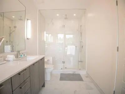 a white bathroom with a shower and a toilet at Casa Lago 5 Bed Waterfront House in Innisfil