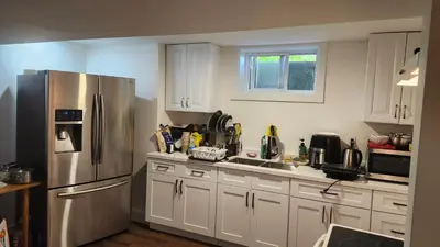 a kitchen with white cabinets and a stainless steel refrigerator at Forest city House -Rooms in a family style in London