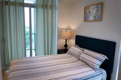 a bedroom with a bed with a window and a lamp at 2bhk Luxury brand new pvt suite Kitchener in Kitchener