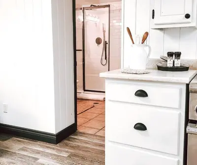 a kitchen with white cabinets and a glass shower door at Cellar Suite at Winery and Vineyard in Waterford