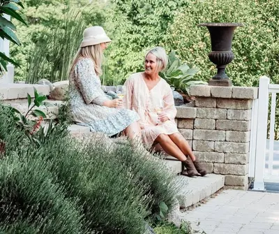 two women sitting on a stone wall in a garden at Cellar Suite at Winery and Vineyard in Waterford