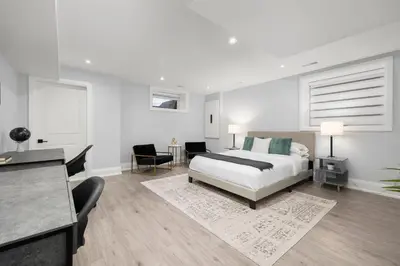 a white bedroom with a bed and a desk at Cozy Modern Custom Built-Free Pkg-Game Room-Heated Floors in Toronto