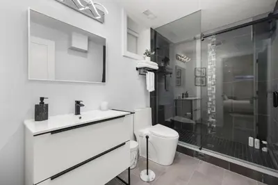 a white bathroom with a sink and a shower at Cozy Modern Custom Built-Free Pkg-Game Room-Heated Floors in Toronto