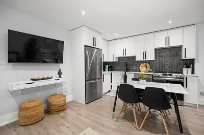 a kitchen with white cabinets and a table and chairs at Cozy Modern Custom Built-Free Pkg-Game Room-Heated Floors in Toronto