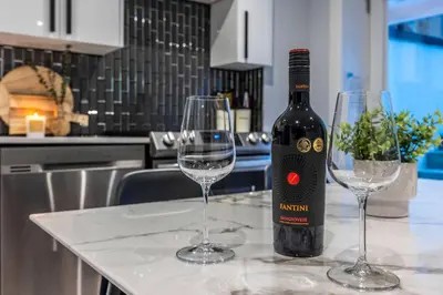 a bottle of wine and two wine glasses on a counter at Cozy Modern Custom Built-Free Pkg-Game Room-Heated Floors in Toronto