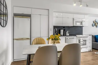 a kitchen with white cabinets and a table with chairs at Beautiful 2 Bedroom Downtown Toronto Condo with free parking in Toronto