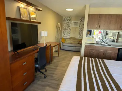 a hotel room with a bed and a desk and a kitchen at Princess Motel in Bobcaygeon