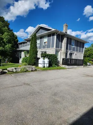 a large house with a driveway in front of it at Princess Motel in Bobcaygeon