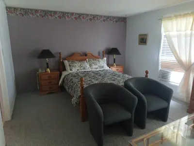 a bedroom with a bed and a pair of chairs at Princess Motel in Bobcaygeon
