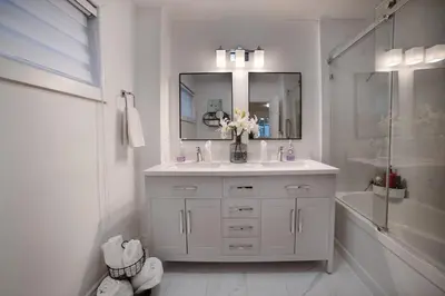 a white bathroom with a sink and a mirror at Muskoka Waterfront Cottage - Moon River with HOT TUB in Bala
