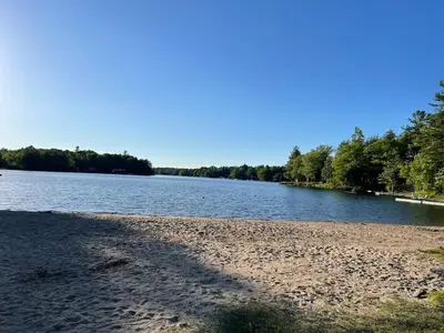 a beach next to a body of water at Muskoka Waterfront Cottage - Moon River with HOT TUB in Bala