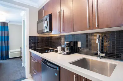 a kitchen with wooden cabinets and a sink and a counter at Sandman Hotel Oakville in Oakville