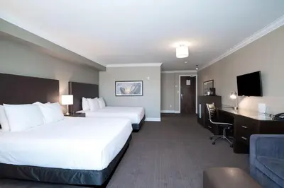 a hotel room with two beds and a desk at Sandman Hotel Oakville in Oakville